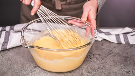 Step by step. Mixing ingredients together in glass mixing bowl for spicy jalapeno cornbread muffins.