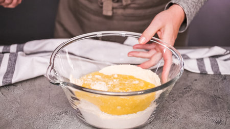 Step by step. Mixing ingredients together in glass mixing bowl for spicy jalapeno cornbread muffins.