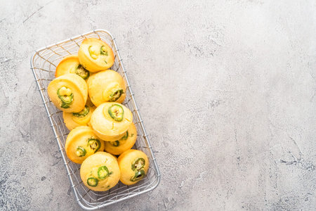 Flat lay. Freshly baked cornbread muffins with spicy jalapeno pepper in wired basket.