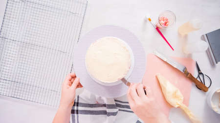 Step by step. Flat lay. Icing tall birthday cake with white buttercream icing.の写真素材
