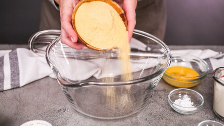 Step by step. Mixing ingredients together in glass mixing bowl for spicy jalapeno cornbread muffins.