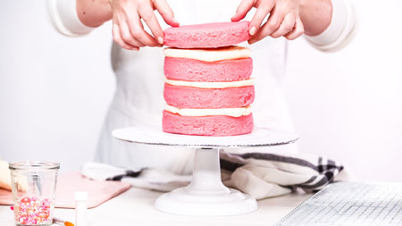 Step by step. Stacking layers together of pink birthday cake.