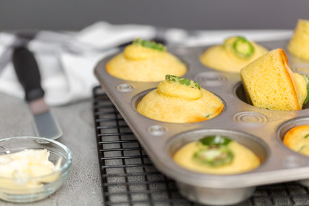 Freshly baked cornbread muffins with spicy jalapeno pepper in muffin pan.