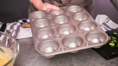 Step by step. Filling metal muffin pan with cornbread batter to bake spicy jalapeno cornbread muffins.の写真素材