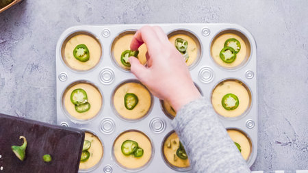 Step by step. Flat lay. Filling metal muffin pan with cornbread batter to bake spicy jalapeno...