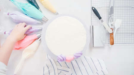 Step by step. Pastry chef piping butter cream frosting on unicorn cake for little girl birthday party.の写真素材