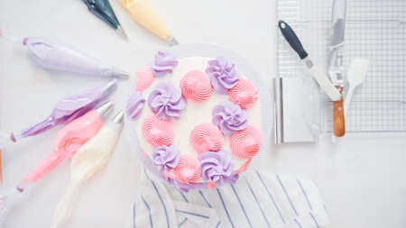 Step by step. Pastry chef piping butter cream frosting on unicorn cake for little girl birthday party.の写真素材