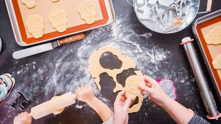 Flat lay. Mother and daughter baking sugar skull cookies for Dia de los Muertos holiday.