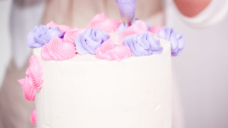 Step by step. Pastry chef piping butter cream frosting on unicorn cake for little girl birthday...