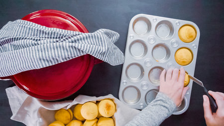 Step by step. Top view. Removing freshly baked cornbread muffins from metal muffin pan.