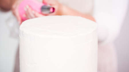 Step by step. Pastry chef piping butter cream frosting on unicorn cake for little girl birthday party.の写真素材