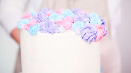 Step by step. Pastry chef piping butter cream frosting on unicorn cake for little girl birthday party.の写真素材
