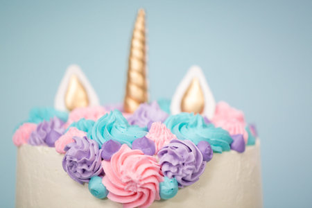 Gourmet unicorn cake with pink and purple buttercream frosting on blue background.