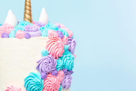 Gourmet unicorn cake with pink and purple buttercream frosting on blue background.