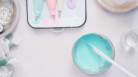 Mixing food coloring into royal icing to decorate unicorn sugar cookies.の写真素材