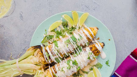 Mexican corn on the cob Elote garnished with spices and fresh cilantro.の写真素材