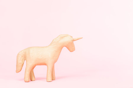 Unfinished paper mache figurine of unicorn on a pink background.の写真素材