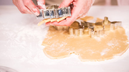 Cutting out sugar cookies with unicorn shaped cookie cutters.