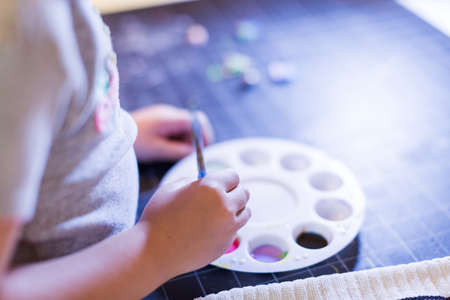 Little girl painting with acrilic paint at her kids desk.の写真素材