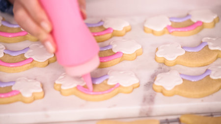 Decorating unocrn shaped sugar cookies with royal icing for little girl birthday party.