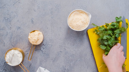 Chopping cilantro on wood cutting board.