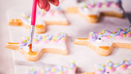Decorating unocrn shaped sugar cookies with royal icing for little girl birthday party.