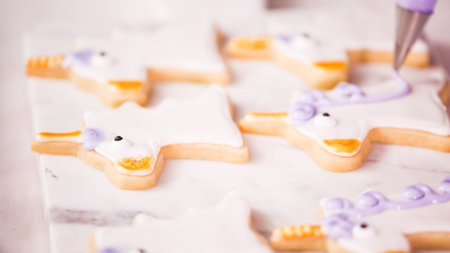 Decorating unocrn shaped sugar cookies with royal icing for little girl birthday party.