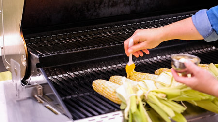 Grilling fresh organic corn on outdoor gas grill to make Mexican corm om the cob elote.の写真素材