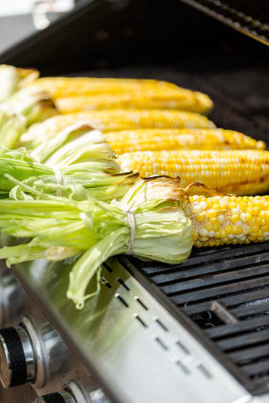 Grilling mexican street corn elote on outdoor gas grill.