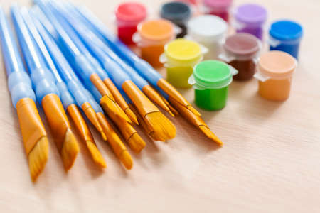 variety of new paint brushes with paint on a wood table.の写真素材