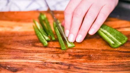 Step by step. Slicing fresh jalapeno pepper on a wood cutting board.の写真素材