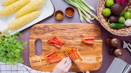 Step by step. Slicing red bell pepper on a wood cutting board.の写真素材
