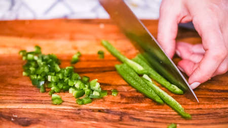 Step by step. Slicing fresh jalapeno pepper on a wood cutting board.の写真素材