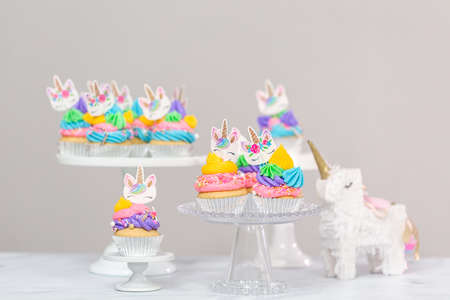 Unicorn cupcakes with multicolor buttercream icing on cake stands.の写真素材
