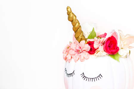 Craft pumpkin painted white and decorated with pink flowers as unicorn on white background.の写真素材