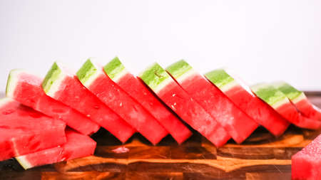 Slicing red woatermelon on a wood cutting board.の写真素材