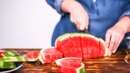 Slicing red woatermelon on a wood cutting board.の写真素材