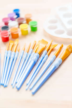 variety of new paint brushes with paint on a wood table.の写真素材