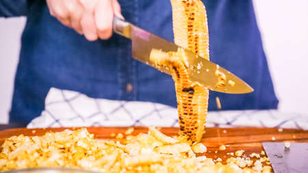 Step by step. Cutting the grilled corn of the cob ona wood cutting board.の写真素材