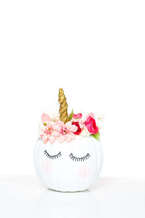 Craft pumpkin painted white and decorated with pink flowers as unicorn on white background.の写真素材