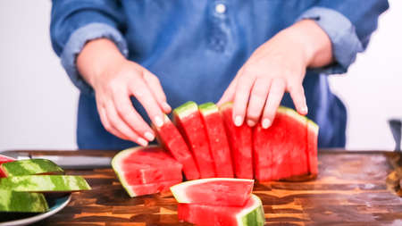 Slicing red woatermelon on a wood cutting board.の写真素材