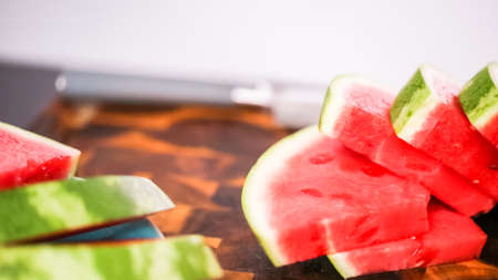 Slicing red woatermelon on a wood cutting board.の写真素材