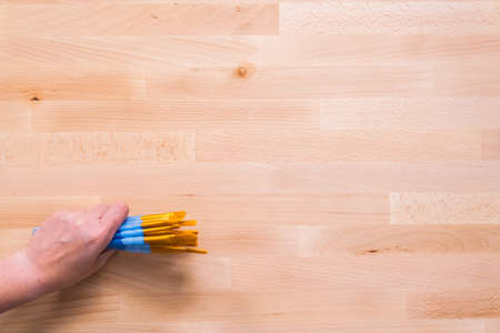 Holding paint brushes on a wood table.の写真素材