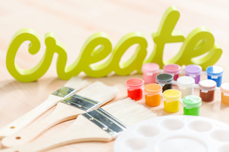 Green create sign with paint brushes on the table.