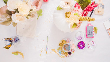 Woman decorating craft pumpkin with unicorn theme for Halloween.