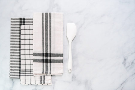 New kitchen towels with simple black pattern folded on marble counter.