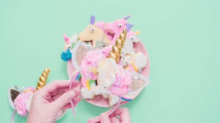 Unicorn shaped sugar cookies decorated with royal icing on pink plate.の写真素材