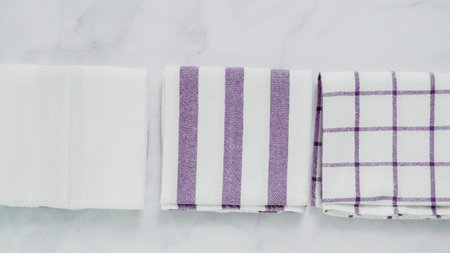 Folding blue and white patterned paper towels on marble surface.