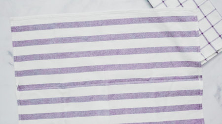 Folding blue and white patterned paper towels on marble surface.