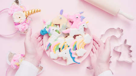 Unicorn shaped sugar cookies decorated with royal icing on pink plate.の写真素材